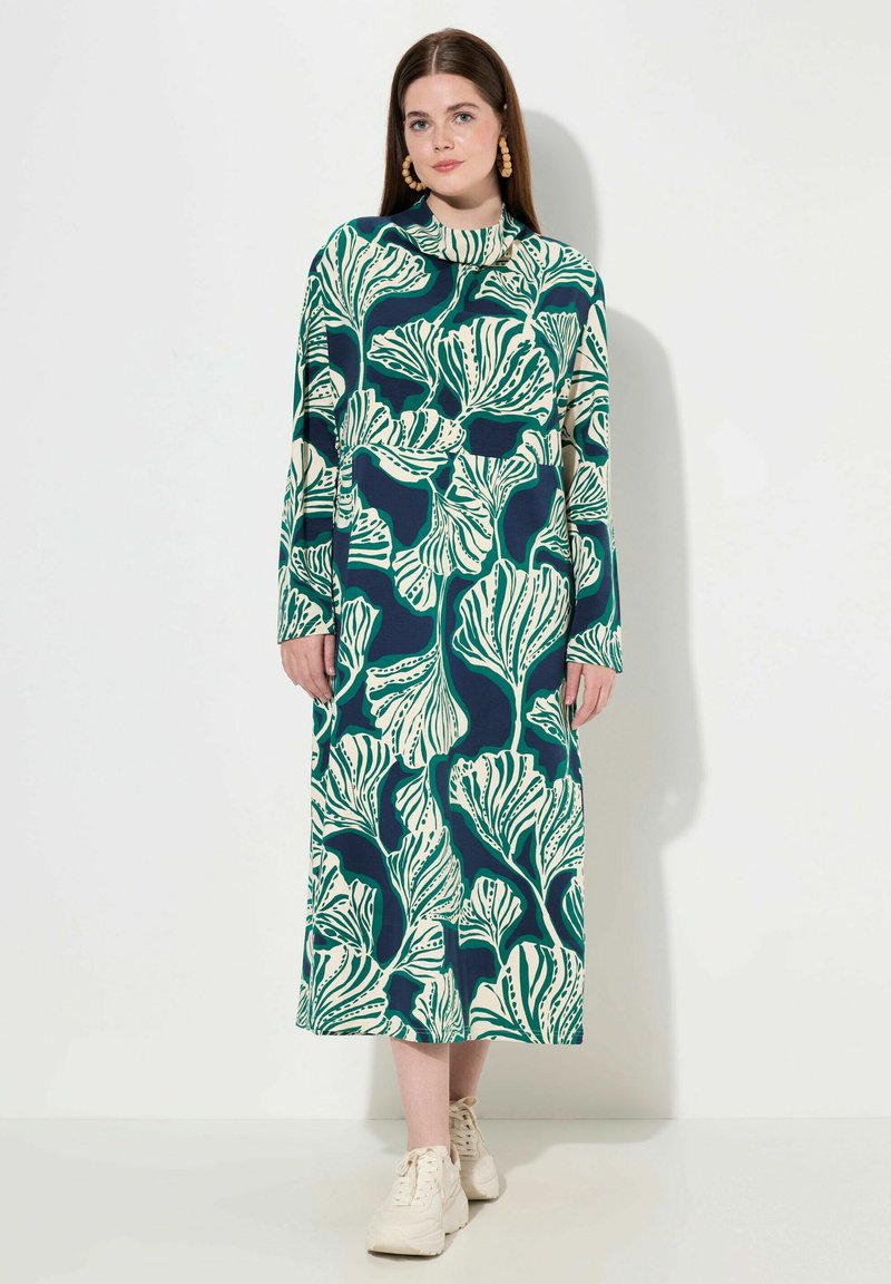 Långärmad klänning i mörkblått med stora gröna och krämfärgade bladmönster; lätt tyg; rund halsringning; design till ankeln.