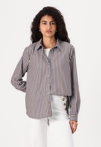 Striped button-up shirt featuring brown and light blue vertical stripes, collared design, and long sleeves. Paired with white pants.