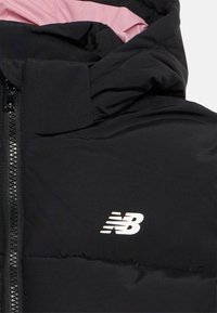 Crna, podstavljena jakna s prednjim patentnim zatvaračem i ružičastim unutarnjim oblogom, s bijelim New Balance logom na prsima.