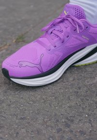 Fialová atletická obuv z priedušného a syntetického materiálu. Má čiernu podrážku s bielymi akcentmi a malým logom Puma na boku.