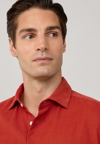 Rotes Cordhemd mit Button-Down-Kragen, aus strukturiertem Stoff und in normaler Passform, vor einem neutralen Hintergrund präsentiert.