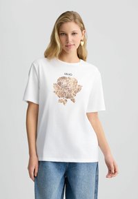T-shirt bianco in cotone con un design di rosa a stampa leopardata e il testo "LIU JO" sopra. La maglietta ha maniche corte e una vestibilità rilassata.