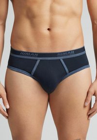 Marineblaue Slips aus weichem, dehnbarem Material. Ausgestattet mit einem passenden dunklen Bund mit Logo und kontrastierenden hellen Nähten.