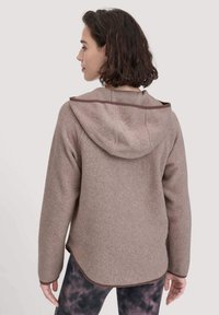 Brauner Fleece-Hoodie mit einer Fronttasche und einer Kordelzugkapuze, mit kontrastierenden Besätzen entlang der Kanten und einer lockeren Passform.