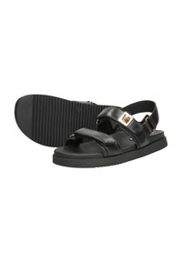 Zwarte leren sandalen met verstelbare banden en een gouden gespaccent. Geprofileerde zwarte rubberen zool voor grip. Open teen ontwerp.