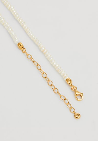 Colar de pérolas com uma corrente de pérolas brancas de formas irregulares, com um fecho em tom dourado e uma corrente de extensão para ajuste de comprimento.