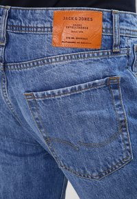 Jeans aus Denim in Mittelblau mit strukturierter Oberfläche. Verfügt über ein braunes Lederpatch mit Branding am Taillenbund und an der Rückentaschennaht.