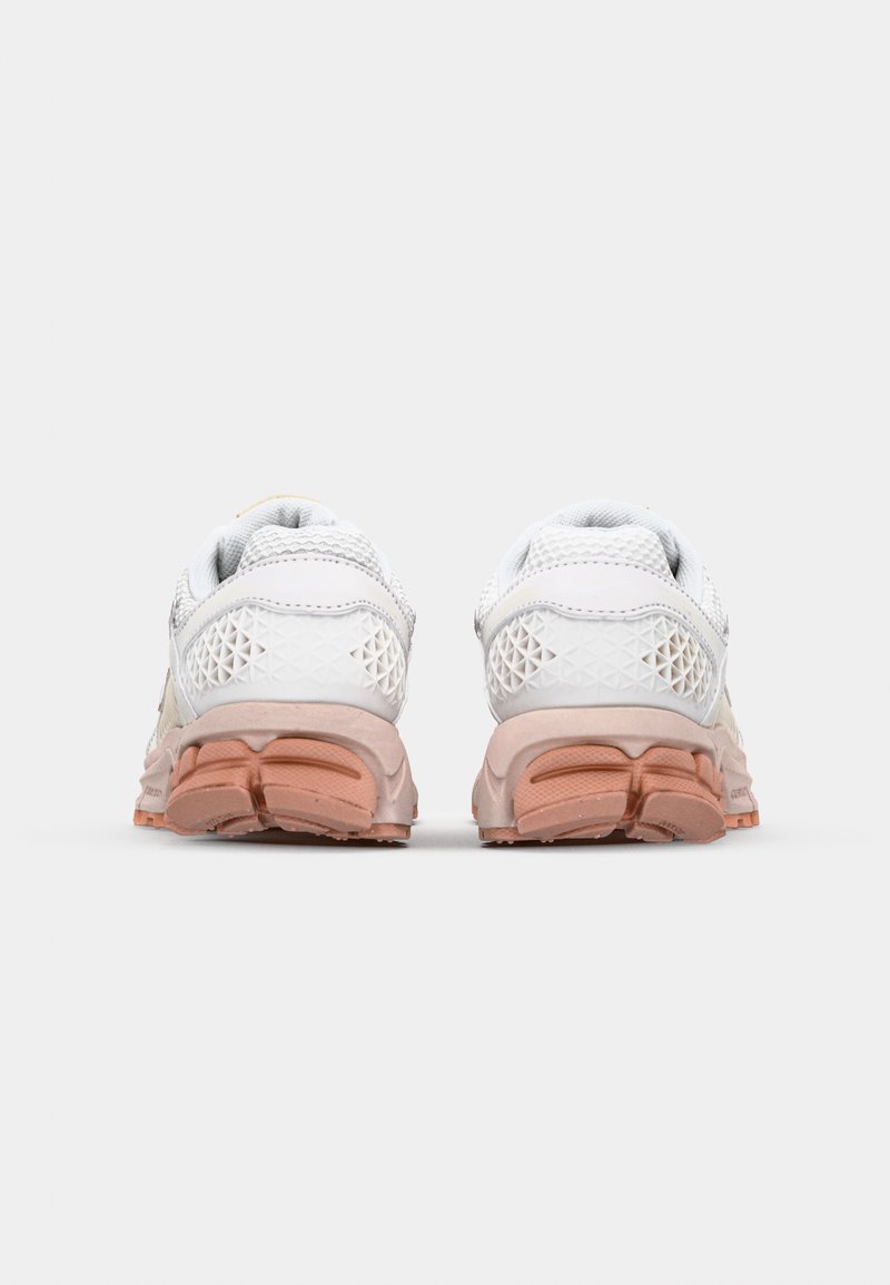 Witte sportieve schoenen met een bovenwerk van mesh, roze rubberen zool en geometrisch patroondetail aan de achterkant. Gevoerde kraag voor comfort.