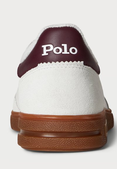 Balti zomšiniai sportbačiai su marono spalvos odiniu kulno užtrauktuku, ant kurio yra balta "Polo" logotipo užrašas. Guma padanga su tekstūruota sąsaja.