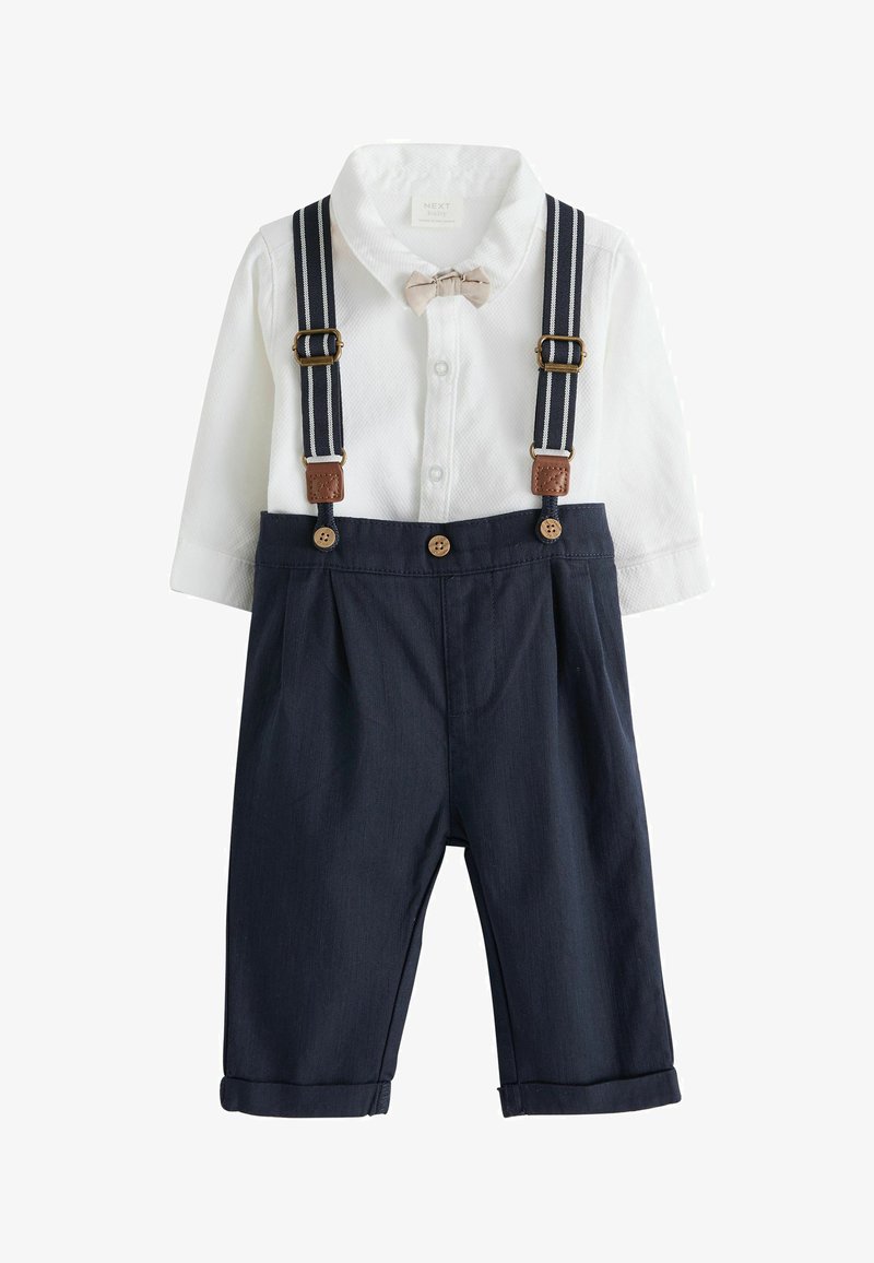 Bílá košile s dlouhým rukávem s texturovaným vzorem, kombinovaná s námořnickými kalhotami s ohrnutými manžetami a tmavě modrými šlemi s hnědými akcenty.