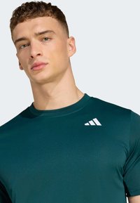 Dark green short-sleeve athletic shirt made from smooth, lightweight fabric; features a white logo on the upper left side.