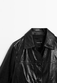 Zwarte leren jas met een glanzende afwerking, voorzien van een kraag met inkeping en knoopsluiting, ontworpen met een gladde textuur en minimale hardware.