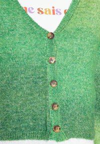 Cardigã verde com decote em V, feito de tecido tricotado texturizado. Apresenta cinco botões castanhos ao longo da frente e um padrão de cor em degradê.