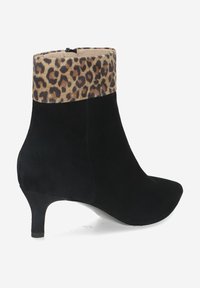 Bottine en suède noir avec un bout pointu et un col en fausse fourrure à motif léopard. Présente un talon fin et une fermeture éclair à l'arrière.