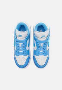 Paire de baskets Nike bleues et blanches vues d’en haut, avec des lacets bleus, une pointe perforée et le logo Nike sur la languette et la semelle intérieure.