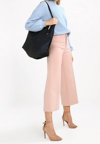 Ljusblå ribbad tröja, ljusrosa vida byxor, bruna högklackade skor och en svart axelväska med silverdetaljer.