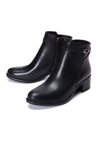 Bottes noires en cuir jusqu'à la cheville avec talons carrés bas, fermetures éclair latérales, et détails décoratifs de sangle et boucle sur fond blanc.