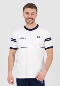 Balta īsām piedurknēm T-krekls ar tumši zilu akcentu, ar apaļu apkakli, svītrām uz piedurknēm un zīmola logo uz krūtīm un sāniem.