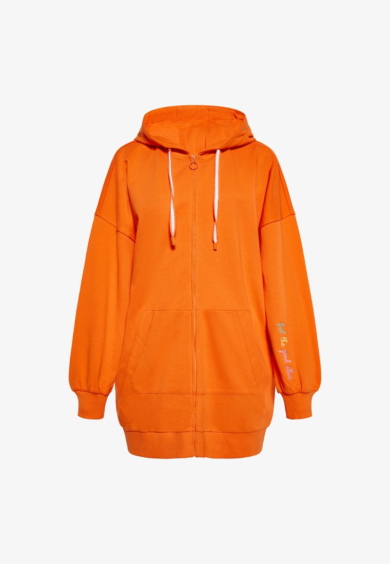 Felpa arancione con zip, realizzata in un tessuto morbido, con cappuccio, cordini bianchi, tasche frontali e dettaglio testuale sulla manica.