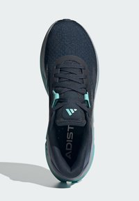 Baskets de sport noires avec une tige en tissu texturé, accents turquoise, lacets plats et semelle rembourrée. Logo présent sur la languette et la semelle intérieure.
