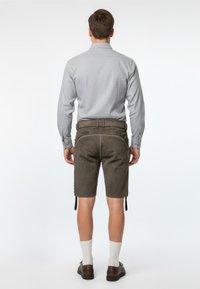 Szary longsleeve z guzikami przy mankietach i wzorzystą teksturą. Brązowe szorty w stylu lederhosen z żółtym przeszyciem i bocznymi trokami. Brązowe buty i białe skarpetki.