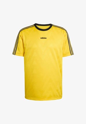 Camiseta amarilla de manga corta con cuello negro y tres franjas negras en los hombros. Presenta un patrón en forma de cheurón sutil y el logo de "adidas".