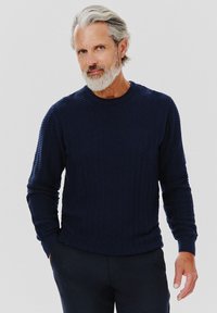 Granatowy sweter dzianinowy z wzorem w zygzak, długimi rękawami oraz ściągaczami na szyi i mankietach. Miękka struktura i swobodny krój.