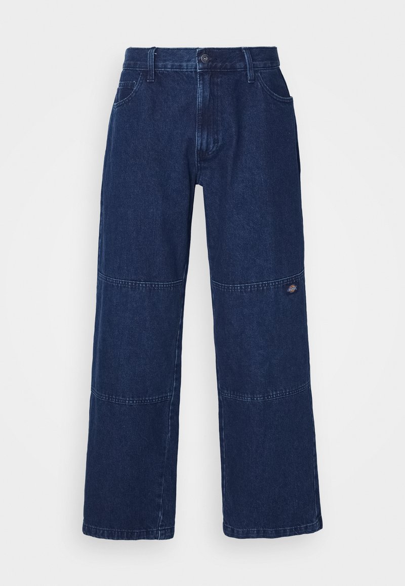 Jean large en denim foncé avec une taille haute, comportant des coutures doubles et un petit logo près du genou. Tissu structuré et résistant.