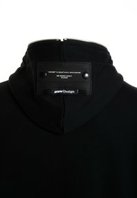 Sudadera con capucha negra de diseño estructurado, que presenta un cuello con cremallera, tela texturizada y una etiqueta de cuero con detalles de marca impresos.