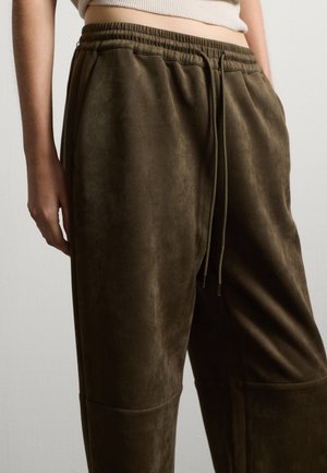 Zachte, olijfgroene joggers gemaakt van suede-achtige stof. Voorzien van een elastische tailleband met trekkoorden en zijzakken. Glad oppervlak overal.