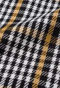 Tissu tissé présentant un motif pied-de-poule en noir, blanc et jaune, avec une surface texturée et des rayures diagonales contrastées.