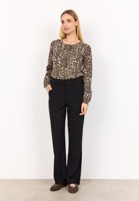 Brun leopardmönstrad blus, svarta byxor och bruna ballerinas med gyllene nitar. Blusen har långa ärmar, rund halsringning och avslappnad passform.