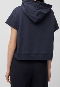 Sudadera corta de color azul marino con mangas cortas, que presenta una capucha con cordón y un dobladillo acanalado. Textura de tela suave, diseño sencillo y mínima marca.