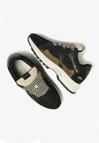 Black and tan sneakers with mesh fabric, suede accents, and rubber soles. Features a woven black-and-white strap across the instep.