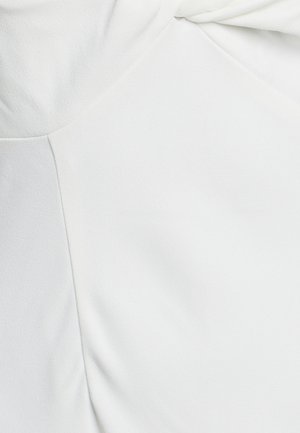 Witte stof met een gladde, matte textuur en subtiele plooien en naden die een vloeiende vormgeving creëren.