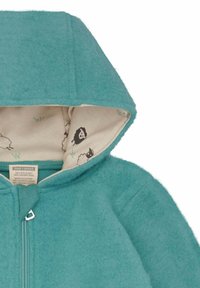 Teal wollen hoodie met een rits aan de voorkant. Voering van een crèmekleurige stof met zwarte schapenpatronen. Zachte textuur met een gestikte afwerking.