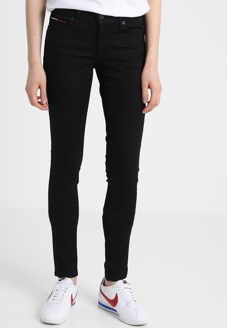 Vaqueros negros ajustados hechos de denim elástico, con una cintura de altura media, un diseño de cinco bolsillos y un sutile acento rojo en el bolsillo delantero.