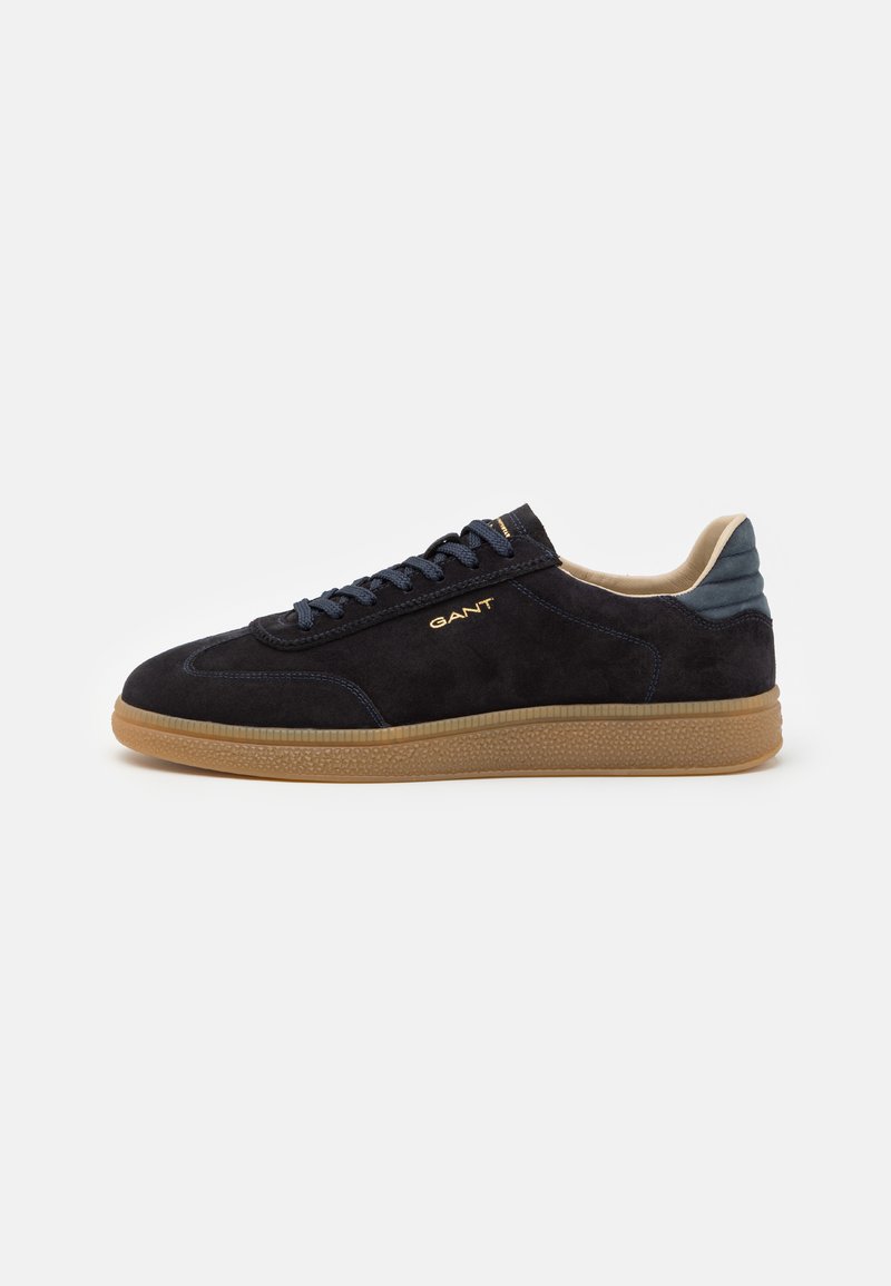 Sorte semskede sneakers med teksturert gummisåle, kontrasterende marineblå detaljer og runde skolisser. Har gullmerke på siden.