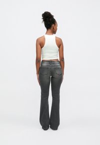 Lahenevad tumedashallid teksad, millel on siledapinnaline viimistlus. Komplektis on vormis valge varrukateta lühike topp, nähtav tagantpoolt. Lihtne disain ja lõige.