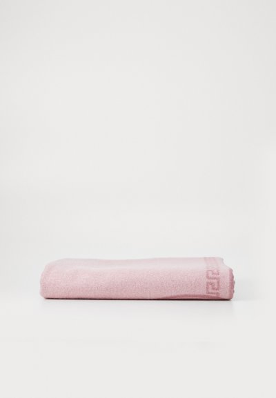 Serviette rose doux, forme rectangulaire, tissu texturé avec un motif géométrique subtil le long du bord. Fabriquée en matériau absorbant.