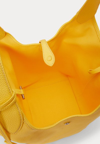 Φωτεινή κίτρινη τσάντα ώμου ανοιχτή, που δείχνει χειρολαβές από υφή δέρματος, ύφασμα στο εσωτερικό και κούμπωμα με κουμπί.