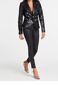Czarna skórzana marynarka o podwójnym zapinaniu, ozdobiona guzikami, zestawiona z czarnymi skórzanymi spodniami z bocznymi suwakami oraz szpilkami w wzór skóry węża.