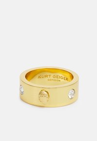 Goudkleurige metalen ring met een centraal sculptuur en twee heldere accentstenen, met een interieurgravure van de merknaam.