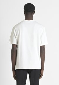 T-shirt bianco a maniche corte, realizzato in cotone, con una vestibilità classica, scollatura rotonda e texture liscia, mostrato da dietro.