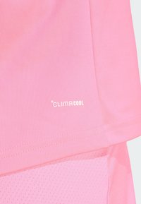 ClimaCool sporta krekls dzīvīgā rozā krāsā. Gluda auduma, ar elpojošu sietu paneļiem. Iezīmējas ar smalku šuvju un logotipa detaļām.