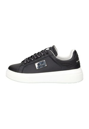 Sneaker nero basse con lati traforati, lacci neri, piastra metallica con logo e suola spessa bianca su sfondo bianco.