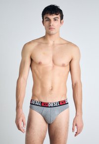 Γκρίζα εσώρουχα τύπου brief με ελαστική ζώνη σε μαύρο και κόκκινο χρώμα, που εμφανίζει με υπερηφάνεια το λογότυπο "DIESEL". Λείος υφασμάτινος σκελετός.