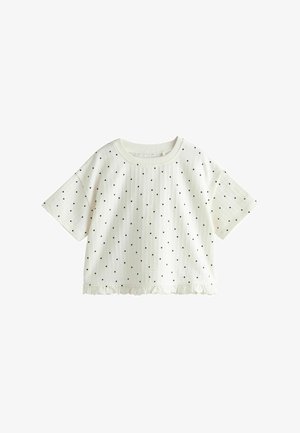 Hvid kortærmet cropped top med sorte polkaprikker og en flæsekant.