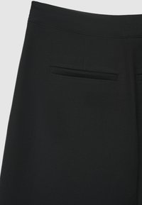 Pantaloni neri con tessuto dalla trama liscia, taglio aderente e due tasche posteriori. Cuciture pulite e design classico per un utilizzo versatile.
