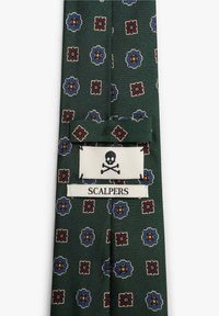 Corbata verde con un diseño estampado que presenta motivos florales en rojo, azul y blanco. Incluye una etiqueta blanca con un ícono de calavera y el texto "SCALPERS".